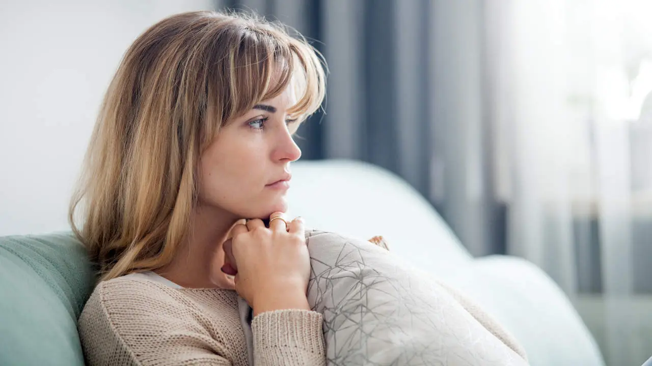 Una chica sentada en el sofá con mirada melancólica salud mental autoestima depresión