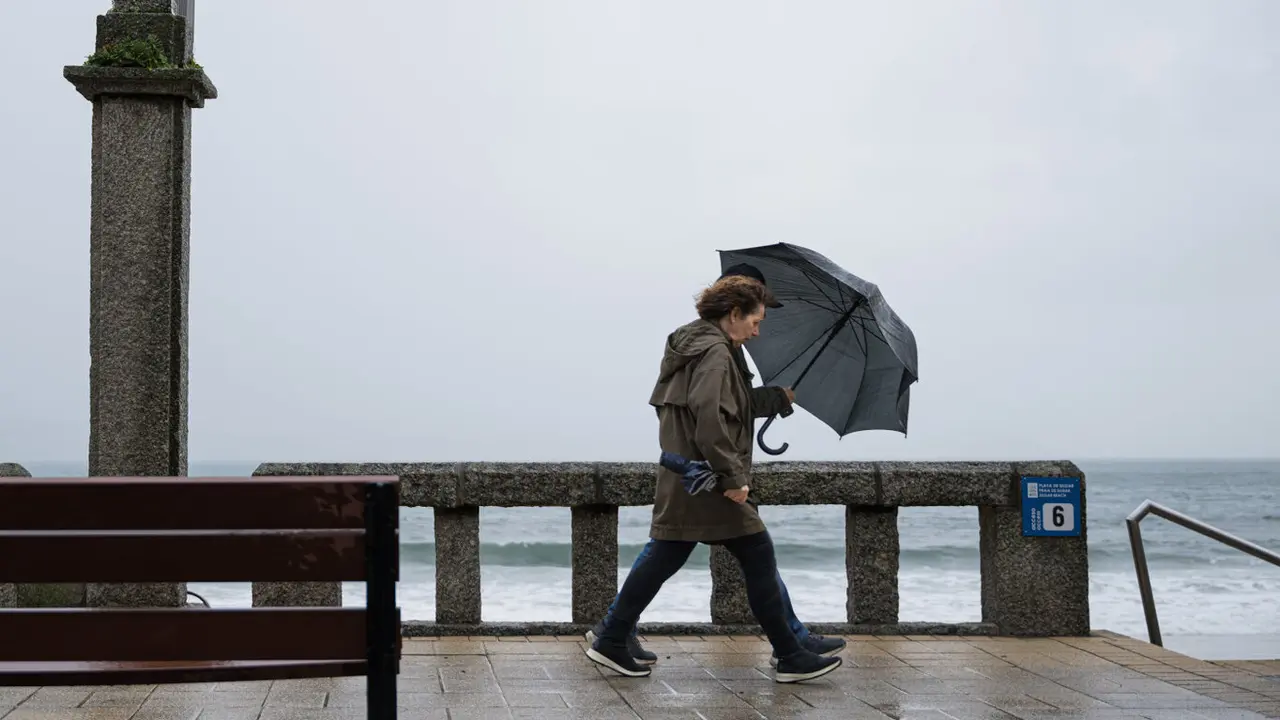 Dos personas se refugian de la lluvia con un paraguas este lunes en la comarca de Salnés. ELENA FERNÁNDEZ (EUROPA PRESS)