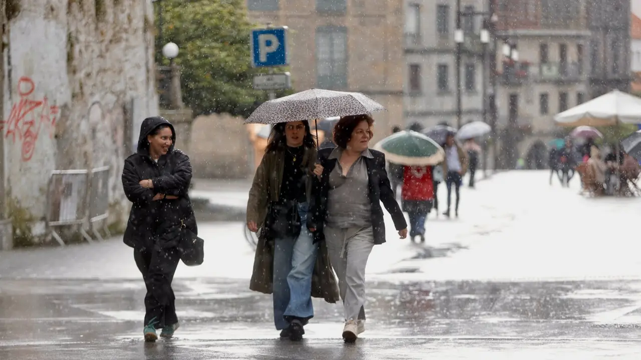 Gente bajo el paraguas este viernes en Pontevedra. RAFA FARIÑA