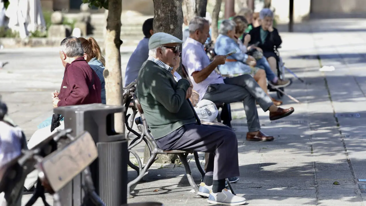 Personas sentadas a la sombra en los bancos de A Ferrería. JAVIER CERVERA-MERCADILLO