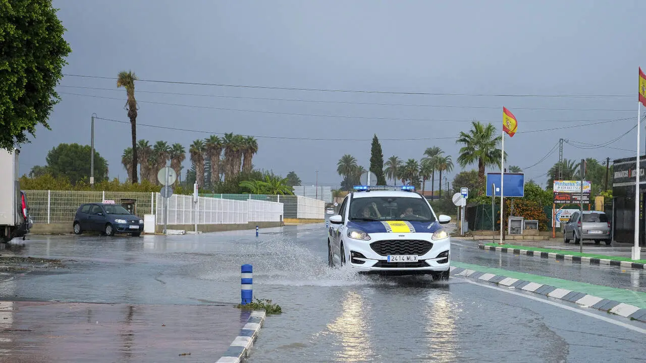 Un coche de Policía circula por una calle anegada por la lluvia, este jueves en Alicante. PABLO MIRANZO (EFE)