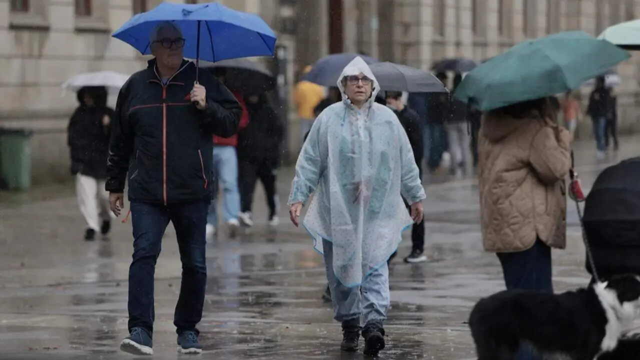 Personas bajo la lluvia, este miércoles, en la avenida de Montero Ríos. JAVIER CERVERA-MERCADILLO