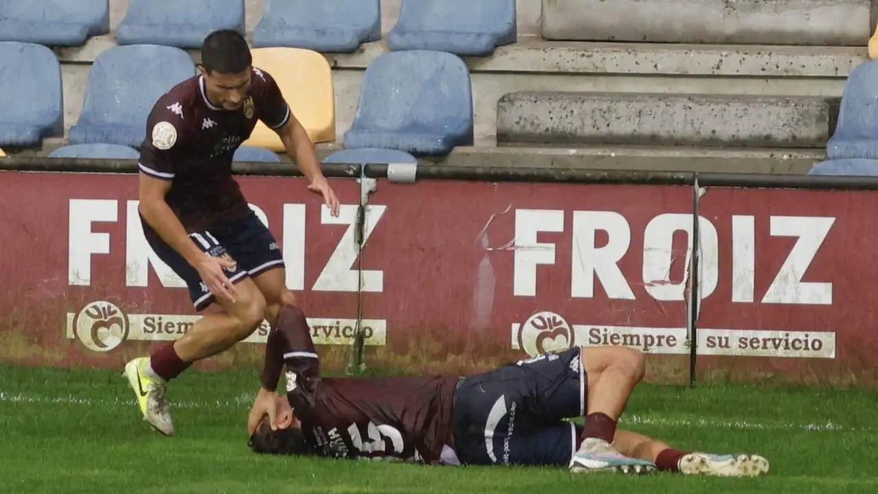 Juanra, en el suelo, en el momento de la lesión ante el Mérida, junto a Miguel Cuesta, quien acudió a ayudarlo. GONZALO GARCÍA