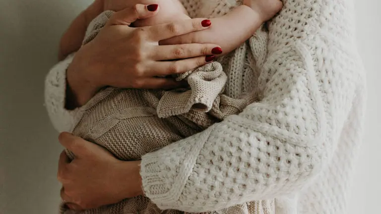 Una mujer sosteniendo a un bebé en brazos. PEXELS